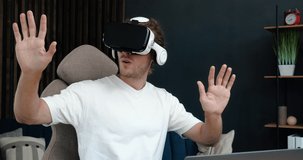Handsome Excites Caucasian Man wearing Virtual Reality Headset at Home. Augmented Reality. Man touching something, using modern 3D VR glasses indoors. Student playing in Glasses at Home. Shot on 4K.