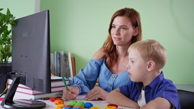 pupil homeschooled, schoolboy with down syndrome doing school homework with female teacher using computer at room during a pandemic