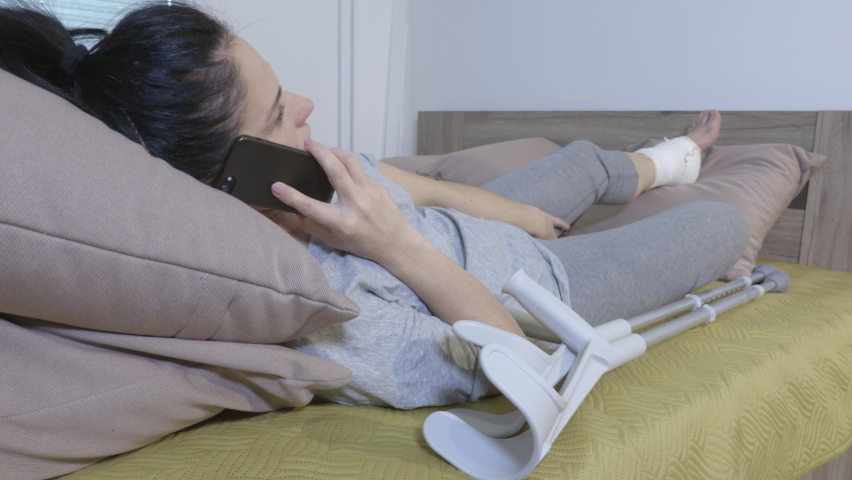 Injured disabled woman lying in bed and using phone | Shutterstock HD Video #1059197507