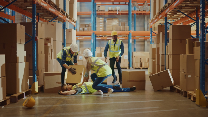 Warehouse Worker Has Work Related Accident Falls while Trying to Pick Up Cardboard Box from the Shelf. Colleagues Call for Help and Medical Assistance. Injury at Work. Slow Motion Royalty-Free Stock Footage #1059197633