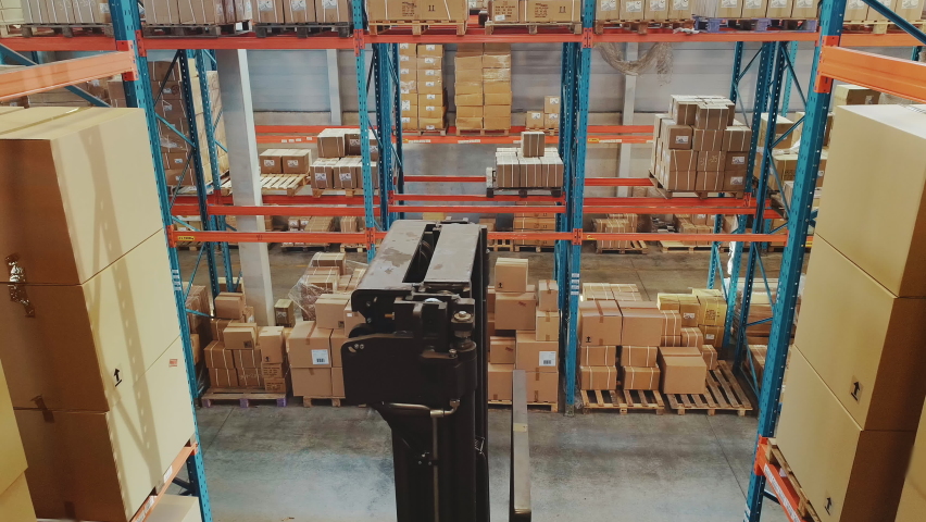 High Aerial Drone Shot: Electric Forklift Truck Operator Lifts Pallet with Cardboard Box of in a Big Retail Warehouse a Shelf. Logistics Product and Goods Delivery and Distribution Center Royalty-Free Stock Footage #1059197675