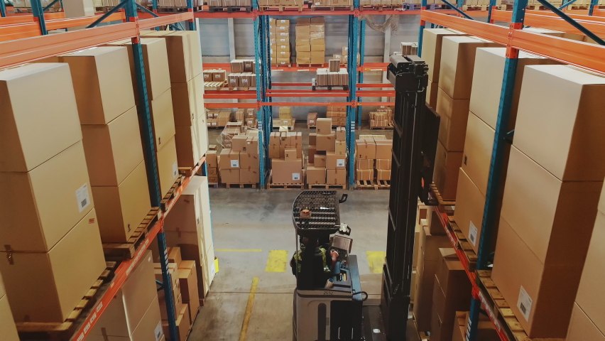 High Aerial Drone Shot: Electric Forklift Truck Operator Lifts Pallet with Cardboard Box of in a Big Retail Warehouse a Shelf. Logistics Product and Goods Delivery and Distribution Center | Shutterstock HD Video #1059197675