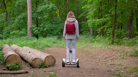 A beautiful girl rides in the woods on a gyrocopter. A girl in jeans, with a red backpack