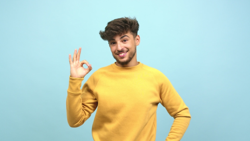 Young arab man cheerful and confident doing ok gesture, excited and screaming, concept of approval and success