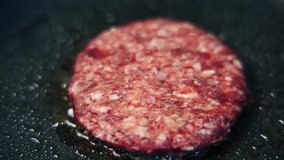 Video clip of burger meat frying on hot pan in close up.Delicious minced beef patty cooking for hamburger dish.Tasty natural food being cooked for dinner meal in American fast food restaurant kitchen