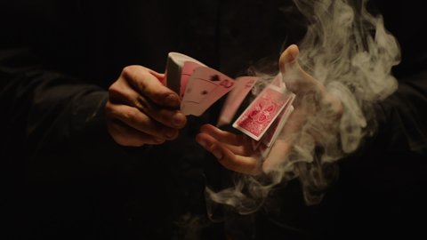 Close-up of a Magician's Hands Performing Card Trick . Throwing and Catching Cards in the Air on black Background with smoke . Card Mechanic .  Shot on ARRI Alexa cinema camera in Slow Motion 