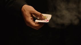 Close-up of a Magician Hand Performing Card Trick . Burning card on black Background with smoke . Card Mechanic rotating flaming ace card in hand . Shot on ARRI Alexa cinema camera in Slow Motion 