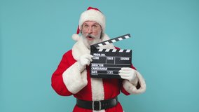 Fun Santa Claus man in Christmas hat red suit coat white gloves glasses рold black film making clapperboard isolated on blue color background studio. Happy New Year celebration merry holiday concept - Powered by Shutterstock - Get 15% off with code: PIKWIZARD15