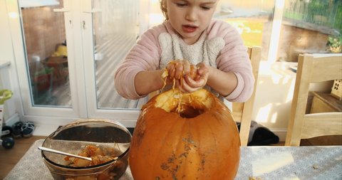 Young girl carving a jack o' lantern out of pumpkin and taking out the oozy slimy insides. Halloween background
