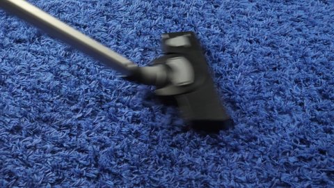 Hoovering blue carpet at home. Household and cleaning concept. Vacuum cleaner in house