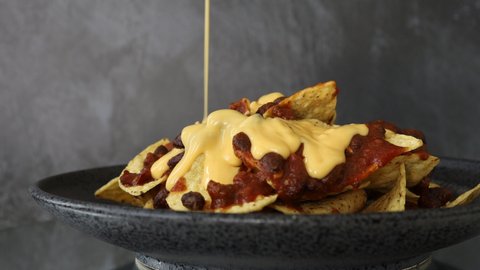 Adding Cheese Sauce to a Plate of Nachos