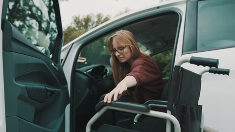 Young disabled person getting out from the car in her wheelchair. . High quality 4k footage