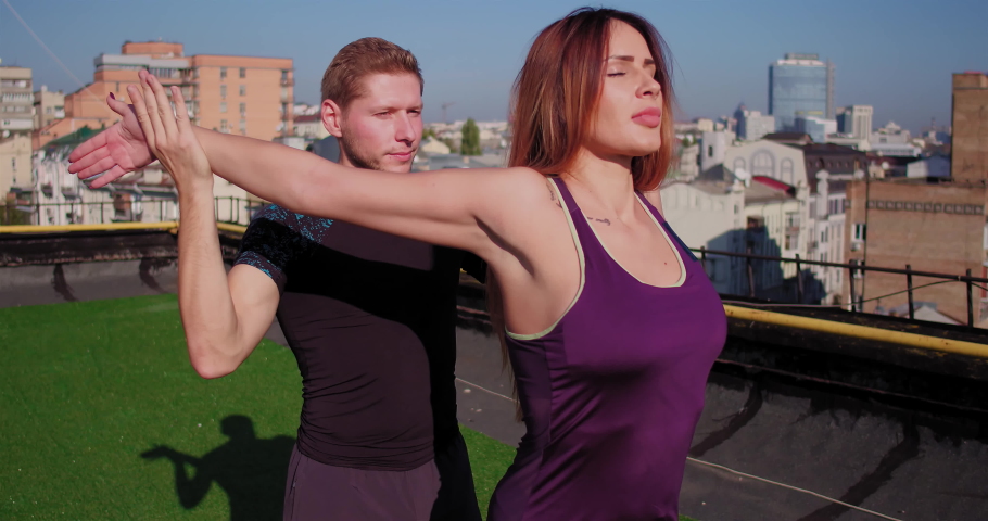 Couple is playing sports on the roof of the building. Guy's stretching the woman. View from the roof in the background. High quality 4k footage. 18 of October 2017. Kyiv, Ukraine. | Shutterstock HD Video #1059220367