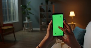 Man lying on couch using smartphone with chroma key green screen at night, scrdoing various gestures like swiping and scrolling - internet, communications concept close up 4k template