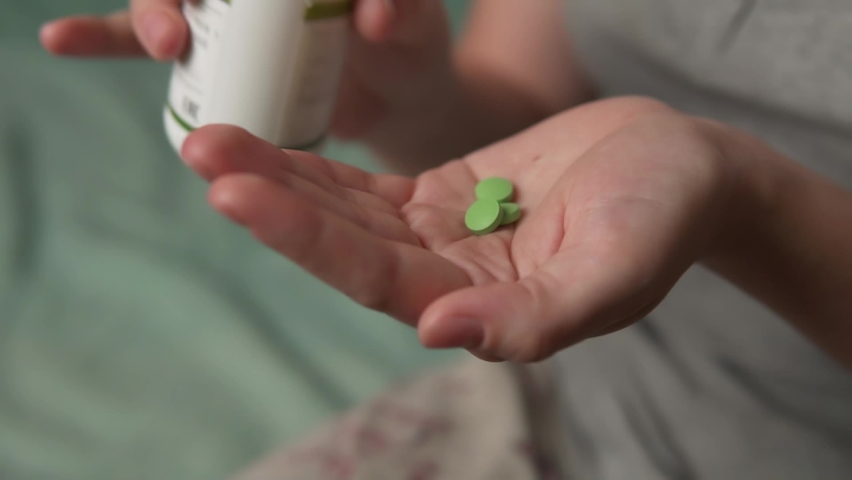 Young woman holding painkiller pills on hand pouring three capsules from meds bottle taking medicine, health care, pharmacy and treatment close up.