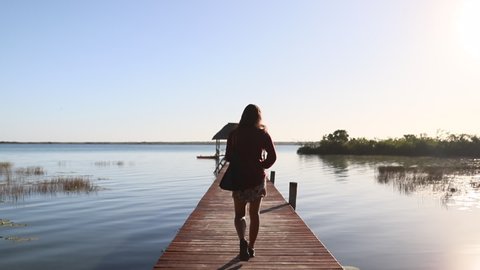 View of a Woman Walking on the Dock on Lake Bacalar with a Beautiful Blue Sky