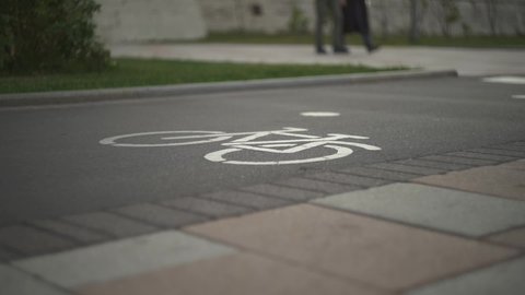 Bicycle road sign has been drawn installed on asphalt. Separate bike path in city center. Pedestrian safety. Man rides a bicycle. Food carrier, healthy lifestyle, comfortable movement around the city
