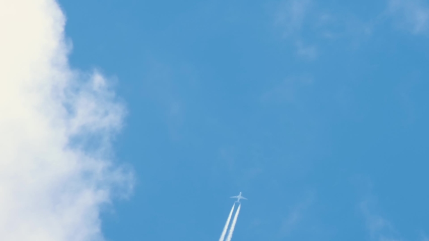 Passenger airplane at cruising altitude with contrail against blue sky. Royalty-Free Stock Footage #1059231614
