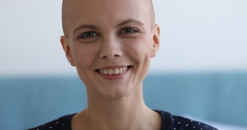 Cancer Survivors Day concept. Close up view face portrait of bald caucasian attractive woman looking at camera having charming wide smile, girl recovered from oncology disease feels happy pose indoors