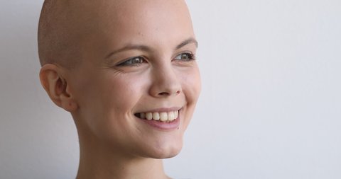 Natural beauty, cancer patient recovery, believe in victory over disease concept. Close up face bald young woman pose on gray studio background having wide charming smile looking at camera feels happy