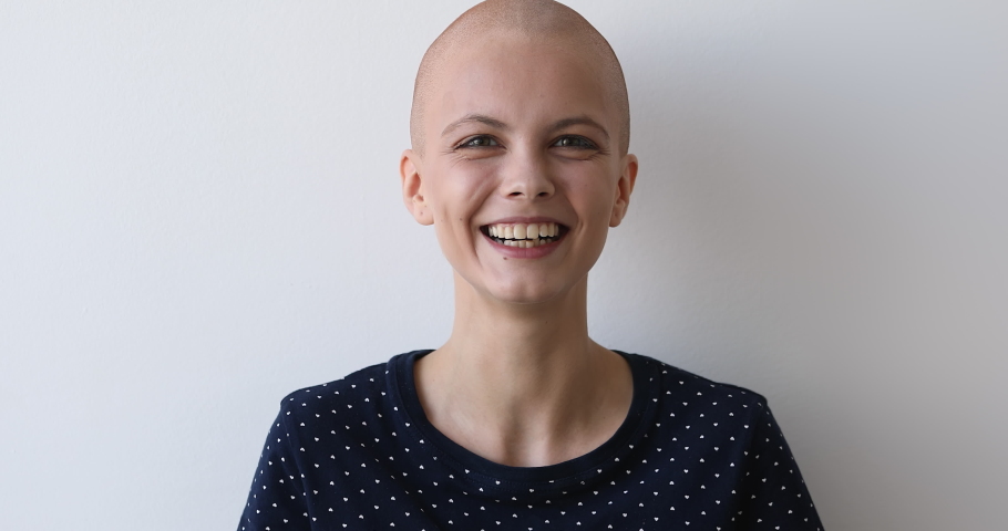 Bald hilarious young woman breast cancer patient posing on grey wall background laughs feels carefree believes in recovery celebrates remission, overcome oncology disease head shot studio portrait Royalty-Free Stock Footage #1059236186