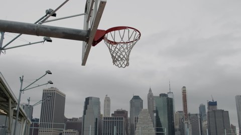 View of a basket on an empty basketball court in NYC, Manhattan business district in the background