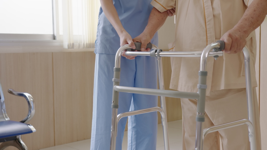 Close up attractive young asian woman or nurse take care senior old man on cane or walker feeling helpful and empathy at nursing home or hospital hallway. Hip, knee and leg problem in older people. | Shutterstock HD Video #1059243485