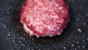 Minced pork meat patty frying on a hot pan in the kitchen, filmed in close up from above.Natural food cooking for dinner in closeup video clip.Raw ground meat fried for burger dish in American diner