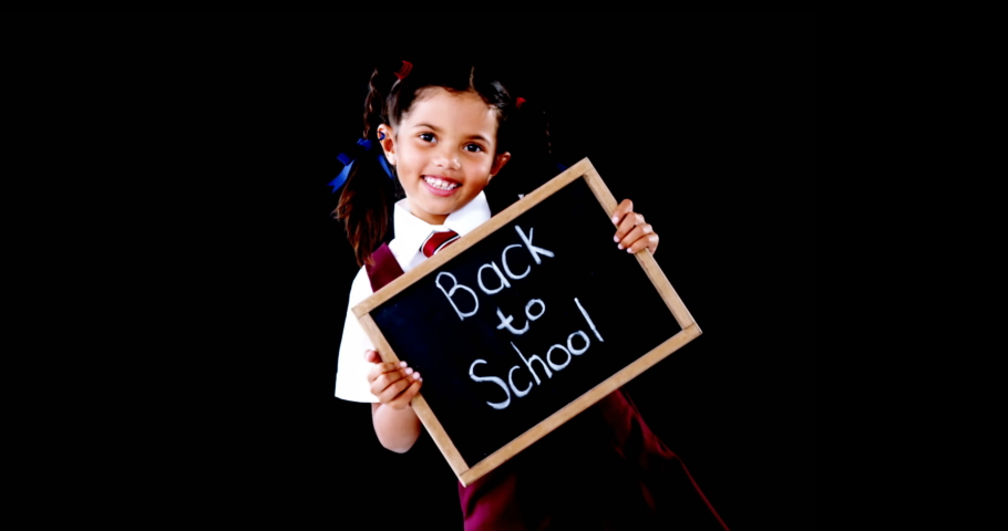 Digital animation of multiple school concept icons moving over school girl holding a slate with back to school text against black background