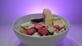 Healthy breakfast with dried fruits, oats and yogurt in a white bowl. Milk pours over it in slow motion