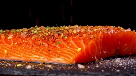 Sprinkling spices on the raw salmon fillet.