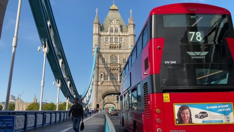 London / United Kingdom - September 18, 2020: Double decker buses, cars and cyclists cross the iconic Tower Bridge during a sunny afternoon.