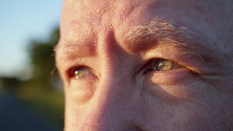 Macro of senior old man face and eyes looking up the sky outside enjoying sunlight. Elderly citizen looks into the distance. Thoughtful vision. True feelings. Eye medicine. Health insurance concept