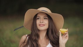 Portrait of a young beautiful woman with white teeth, a beautiful smile in a straw hat holds a lemon next to her face