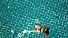 Young woman swimming in open green swimming pool. Outdoor activities. Healthy lifestyle. Top view aerial video 4k.