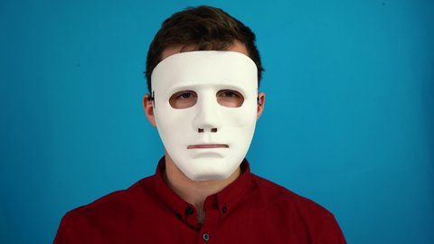 man removes an anonymous mask on a blue background