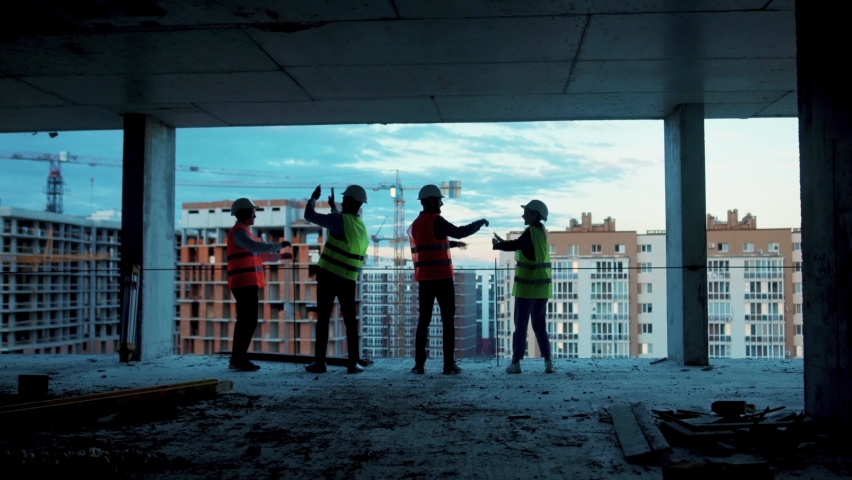 Shot back happy builders engineers workers in hard hat team stand give five each other on construction at sunlight survey urban meeting skyscraper architect contractor inspector helmet slow motion Royalty-Free Stock Footage #1059264602