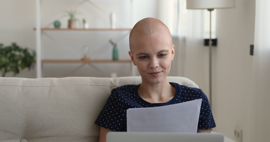 Young bald after chemotherapy woman cancer patient female sitting on couch at home holding paper sheets feels happy woman reading test about health results. Remission oncology disease recovery concept Royalty-Free Stock Footage #1059275207