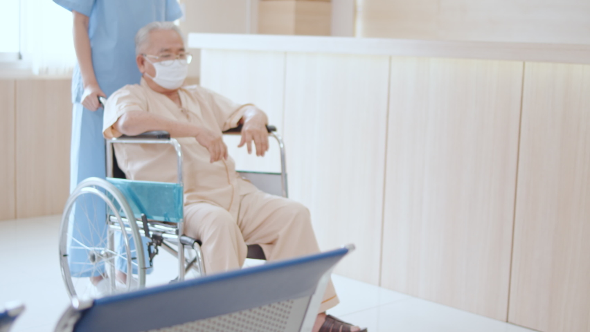 Nurse push Asian senior adult patient wheelchair in hospital hallway, young male doctor crouch down holding hand and talk to the patient with care. Medical healthcare job, or hospital business concept Royalty-Free Stock Footage #1059276587