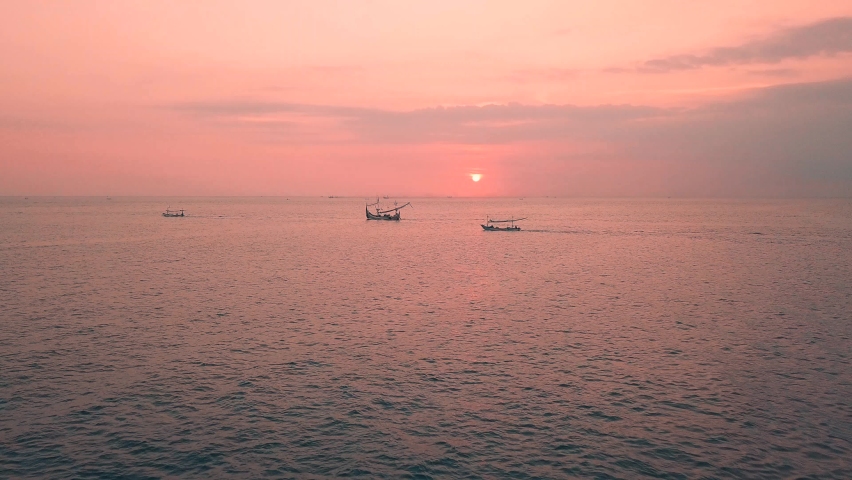 Pink sunset above the sea surface with balinese traditional boats