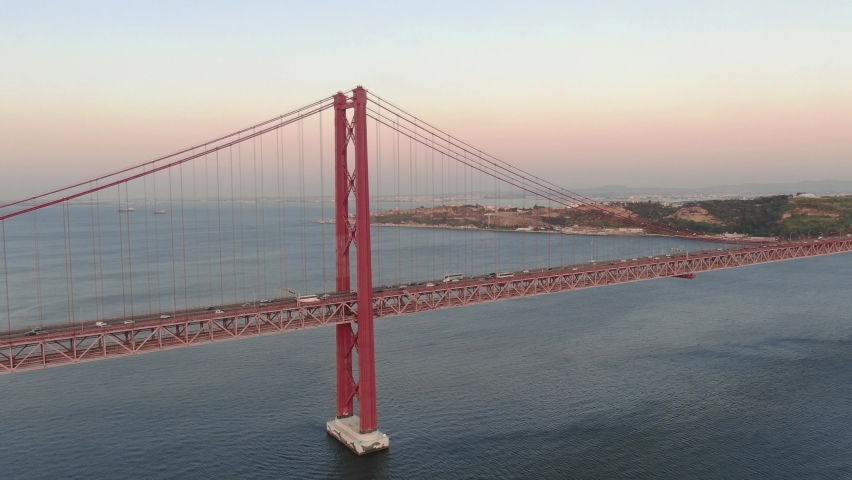 Aerial close up view of Lisbon Ponte 25 de Abril suspension bridge cars driving at sunset, Portugal Royalty-Free Stock Footage #1059281252