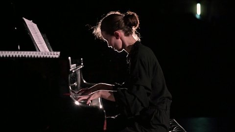 Slow motion of vigorous piano playing. The pianist performs on stage in the spotlight