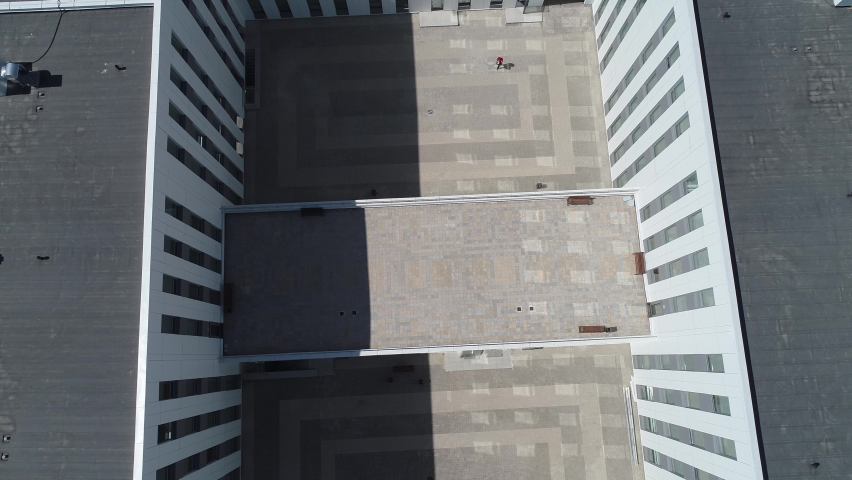 A man walks through an empty courtyard of an office building. The courtyard of the administrative building is surrounded by a wall on all sides. Aerial view