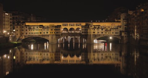 Medium shot of Ponte Vecchio during the night with the reflection on the Arno river