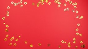 Stop motion animation christmas tree made of balls decoration on red background with golden confetti stars. Concept holiday atmosphere, new year, celebration, video greeting card. Flatlay, top view
