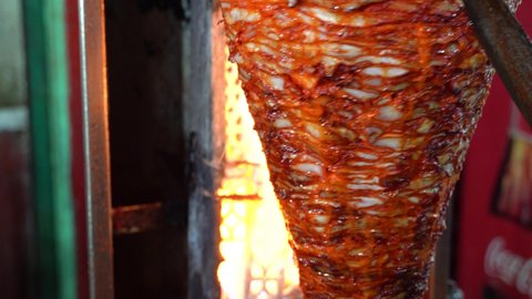 Closeup of a knife turning and slicing the Mexican specialty of al Pastor pork which is fast street food.