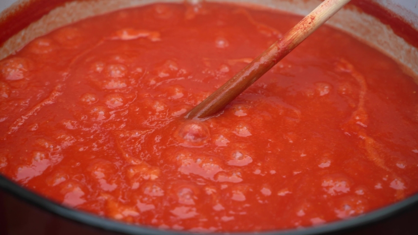Close up on big pot with wooden spoon stirring hot ketchup or tomato sauce or soup while cooking outdoor - homemade with traditional recipe organic food concept | Shutterstock HD Video #1059298940