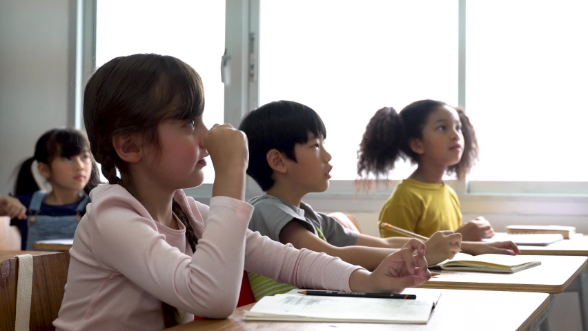 Elementary age Asian student boy raised hands up in Q & A class. Diverse group of pre-school pupils in elementary age in education building school. Volunteering and participating classroom concept. Royalty-Free Stock Footage #1059306824
