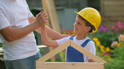 Father and son happy Family concept. Little boy child and his dad engineer builder architect with construction yellow helmet outdoors. Future profession, big dream, building work concept, 4 K slow-mo
