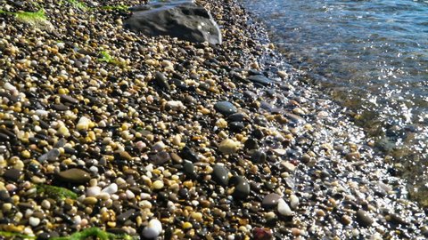 Transparent sea wave washes pebble shore